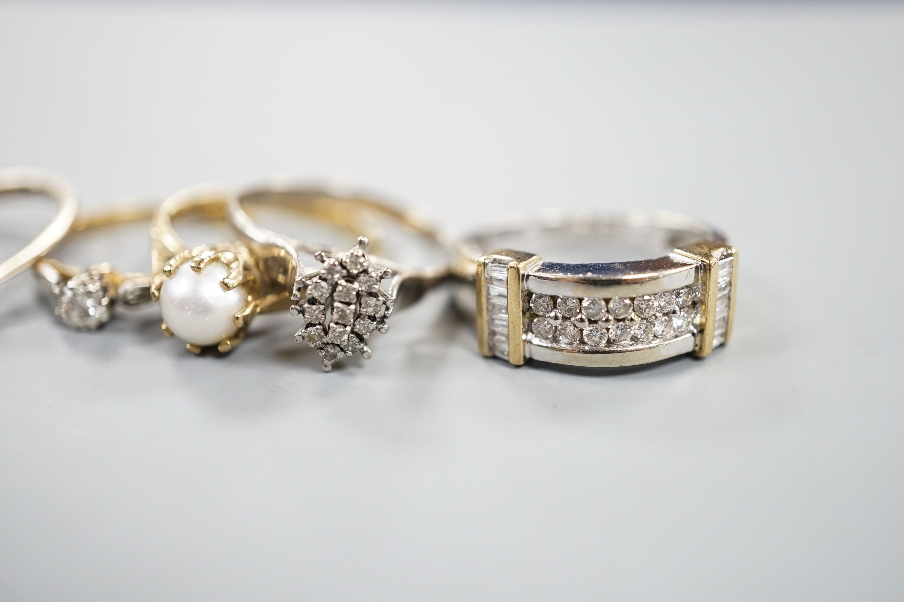 A 750 white metal and solitaire diamond ring, size K, gross 2 grams, two other yellow or white metal diamond set rings, gross 3.4 grams and two 9ct and gem set rings including cultured pearl, gross 6.3 grams.